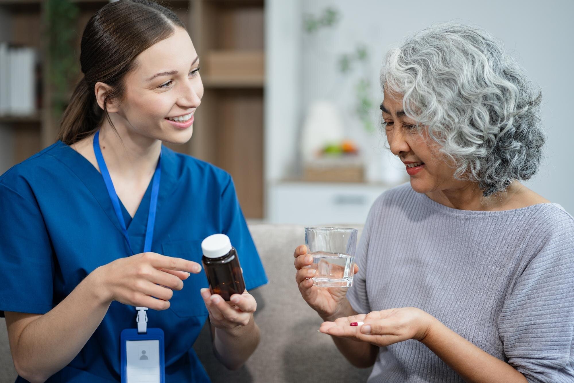 Pflegekraft berät eine Seniorin zur Medikamenteneinnahme